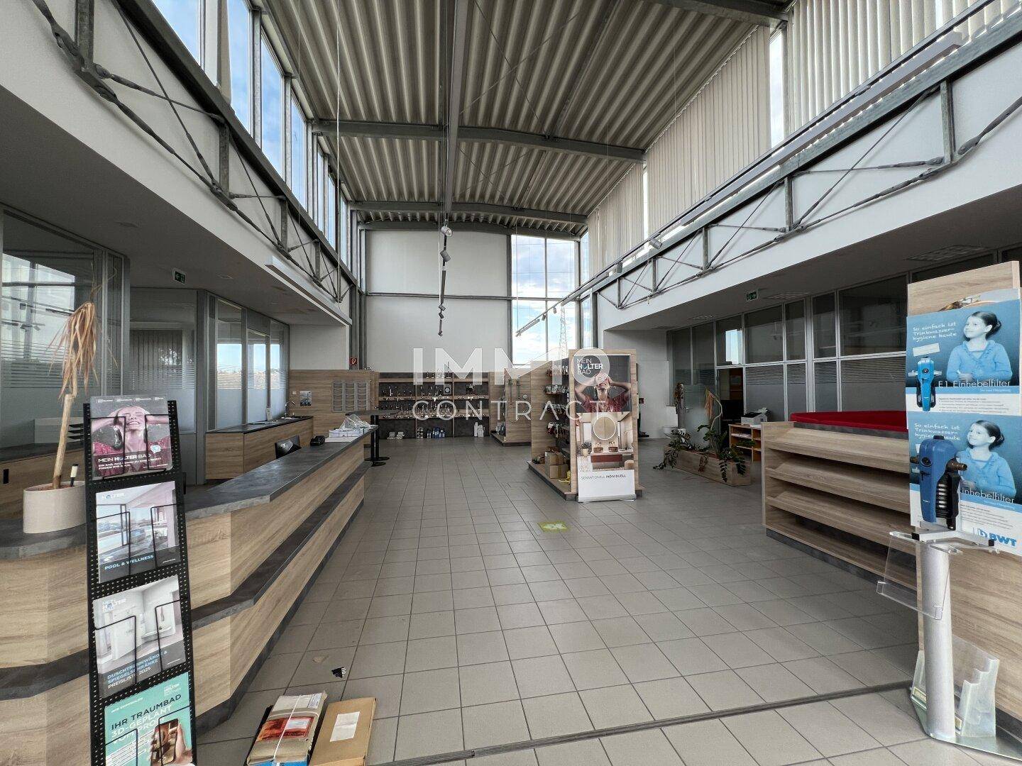 Großer, heller Verkaufsraum mit hohen Decken, Fliesenboden und Glaswänden, ideal für Produktpräsentationen.