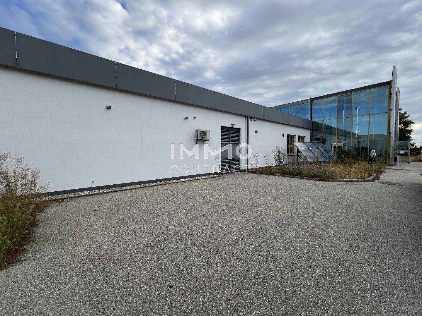 Seitenansicht des Gewerbegebäudes mit moderner Glasfassade und Parkflächen.