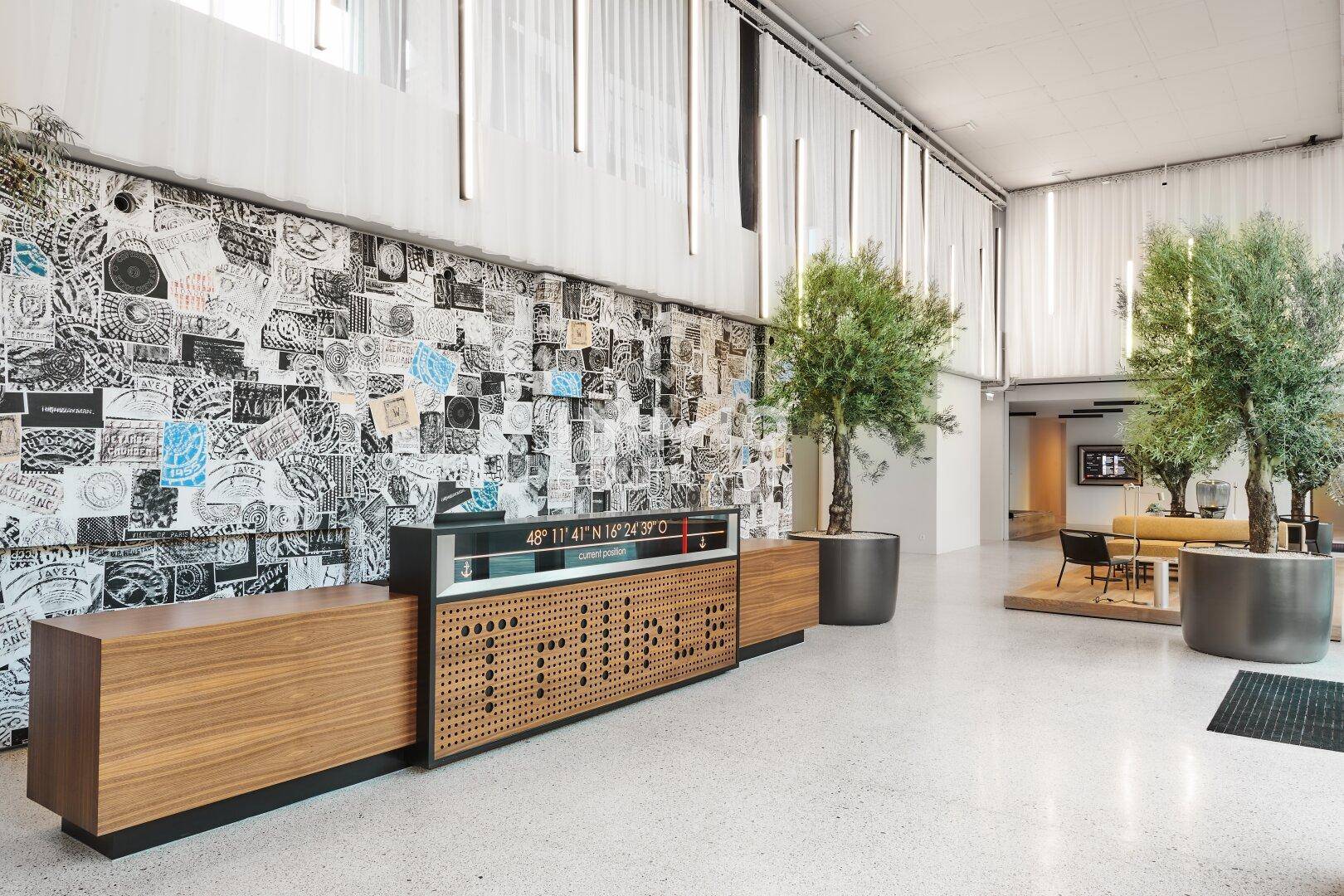 Elegante Lobby mit künstlerischer Wandgestaltung, großen Pflanzen und modernen Sitzbereichen.