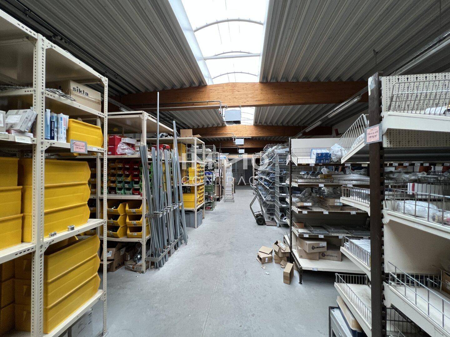 Lagerhalle mit Regalsystemen für Kleinteile und Materialien, gut beleuchtet durch Oberlichter.