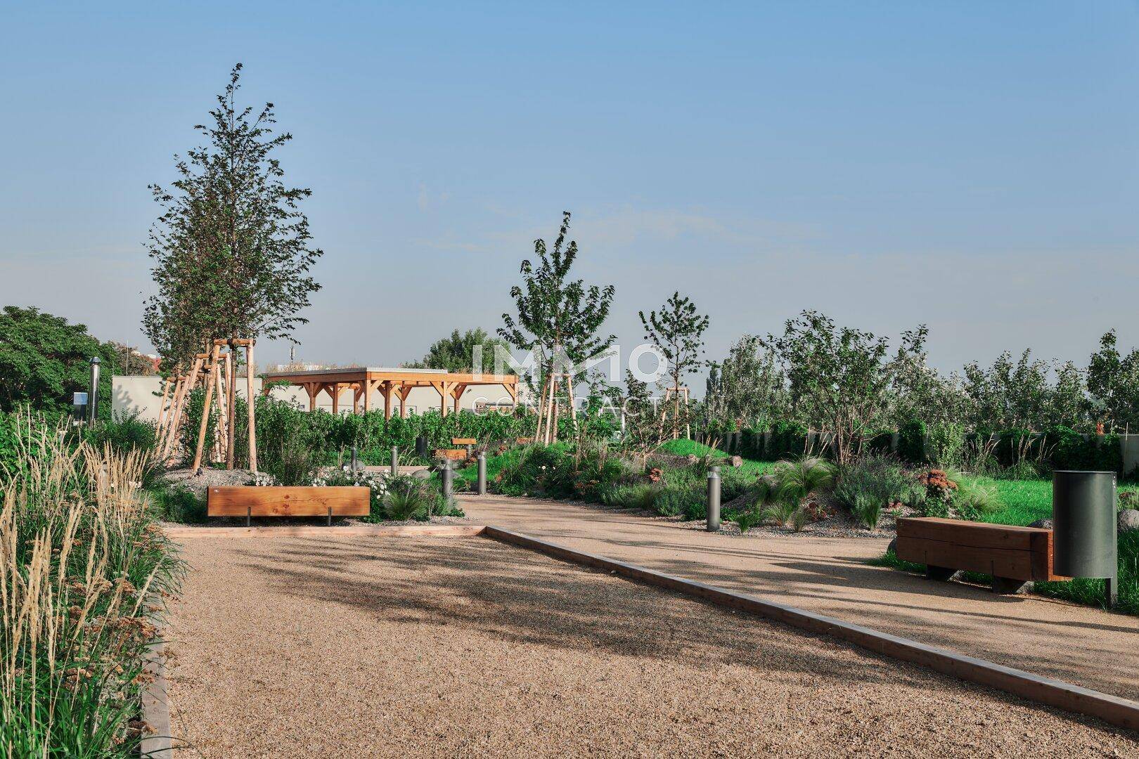 Gartenweg mit Kies, Sitzbänken und üppiger Bepflanzung in einer modernen Anlage.