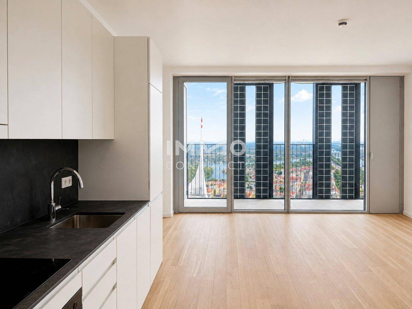Moderner offener Wohn- und Küchenbereich mit Holzboden und weitem Blick über die Stadt.