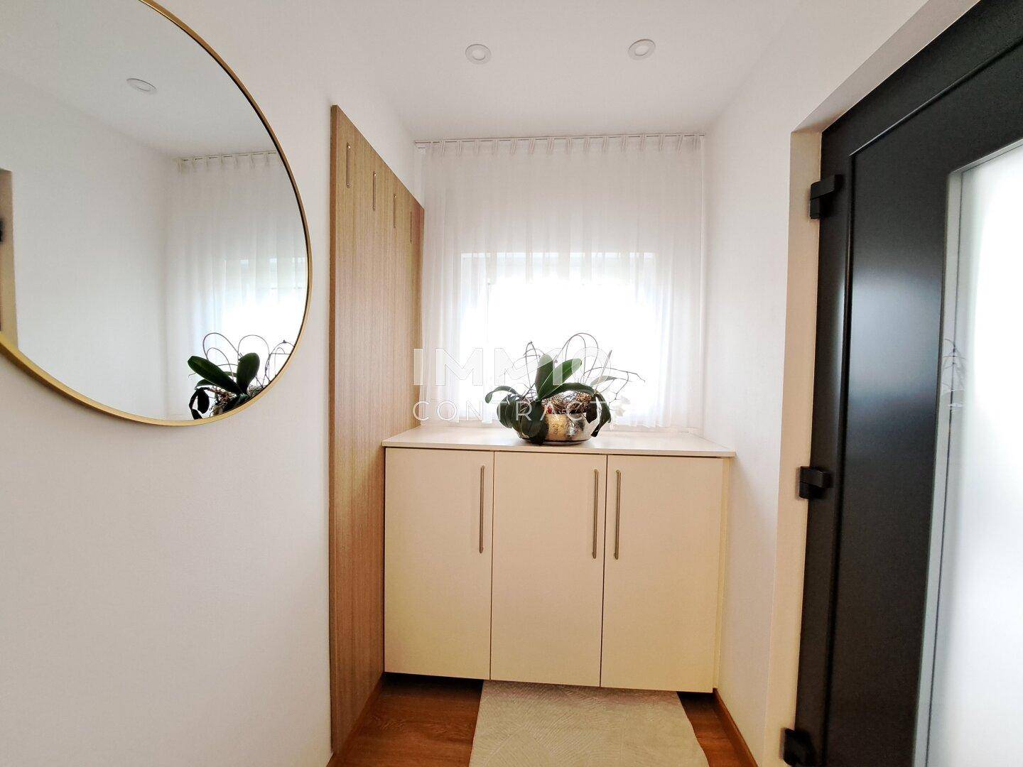 Heller Eingangsbereich mit Garderobe, Spiegel und Holzboden.