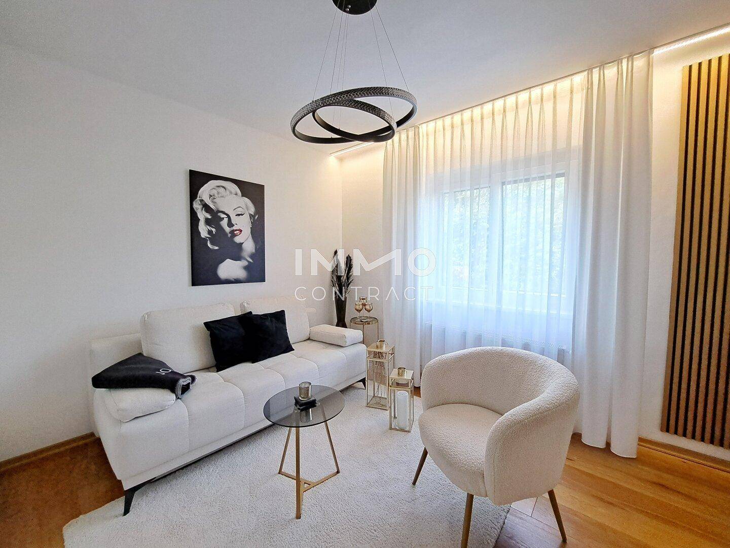 Stilvolles Wohnzimmer mit weißem Sofa, Holzboden und moderner Kunst an der Wand.
