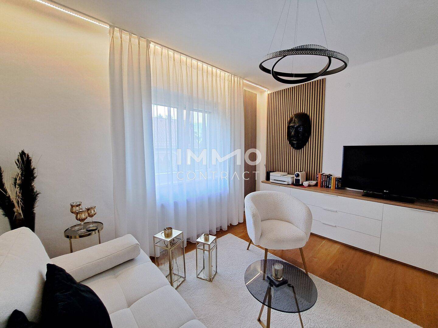 Modern eingerichtetes Wohnzimmer mit Holzboden, weißem Sofa und stilvoller Wandverkleidung.