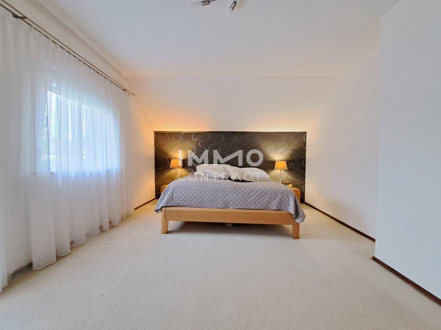 Geräumiges Schlafzimmer mit Doppelbett, Teppichboden und indirekter Beleuchtung.