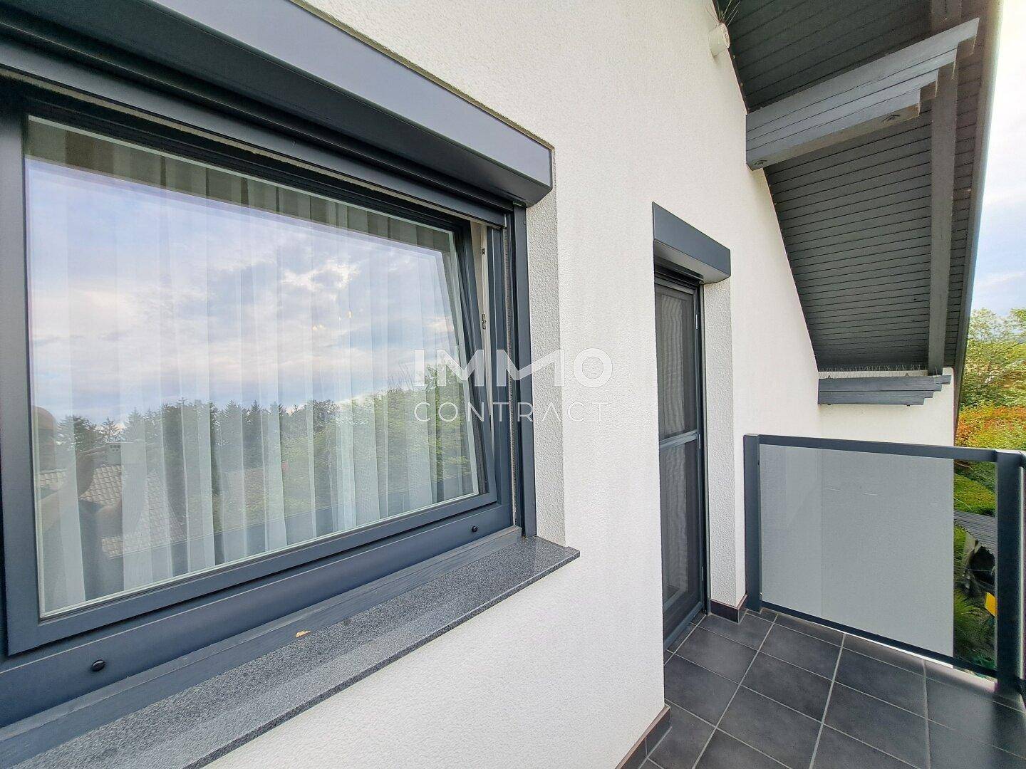 Kleiner Balkon mit Glasbrüstung und Blick ins Grüne.