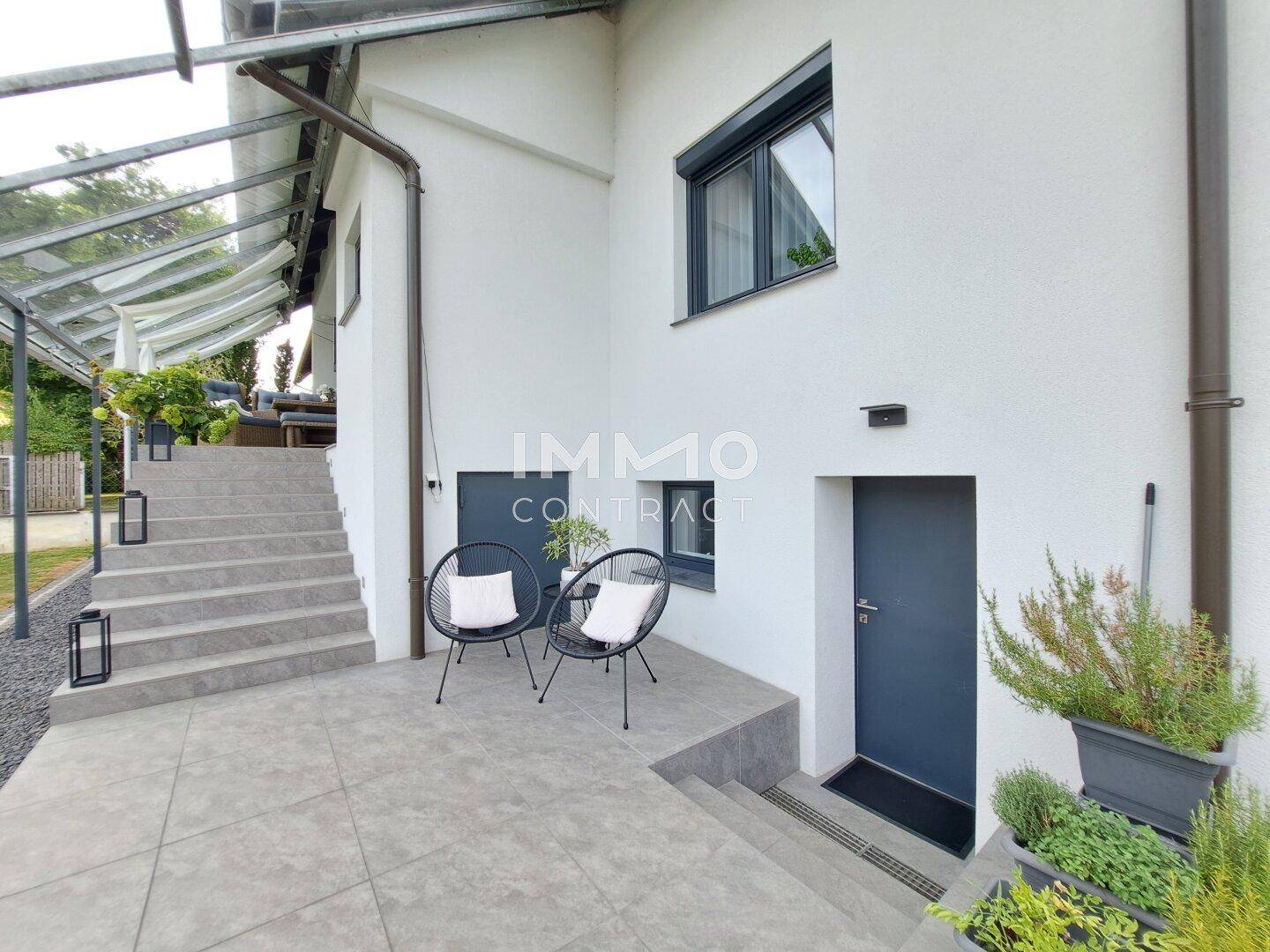 Kleiner gepflasterter Sitzbereich im Freien mit Pflanzen und Zugang zum Haus.