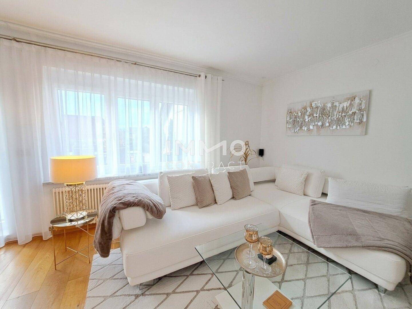 Gemütliches Wohnzimmer mit weißem Ecksofa, Holzboden und dekorativer Beleuchtung.