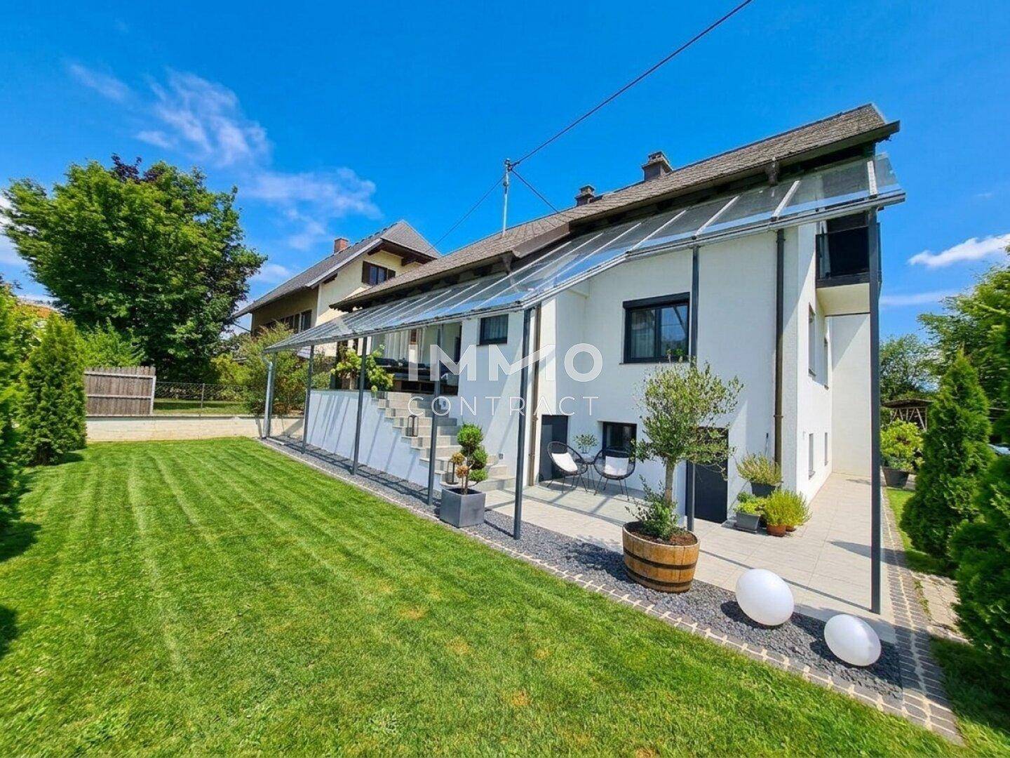Modernes Einfamilienhaus mit gepflegtem Rasen und überdachtem Terrassenbereich.
