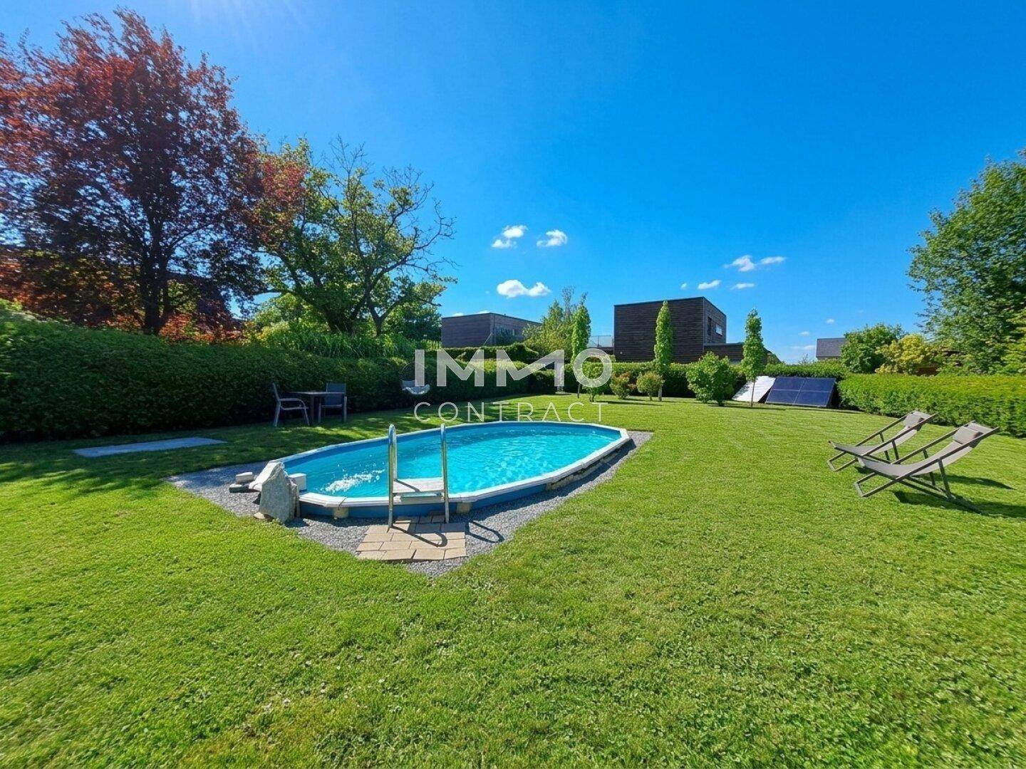 Weitläufiger Garten mit Pool, umgeben von Rasen und Bäumen, inklusive Solarpaneelen.