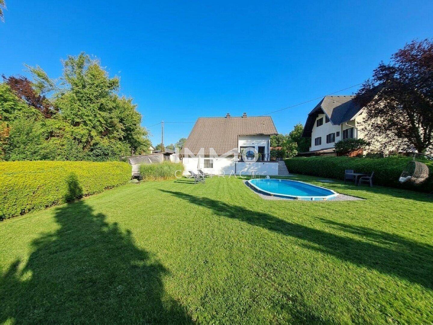 Ansicht des Hauses vom Garten aus mit einem Pool und gepflegter Rasenfläche.