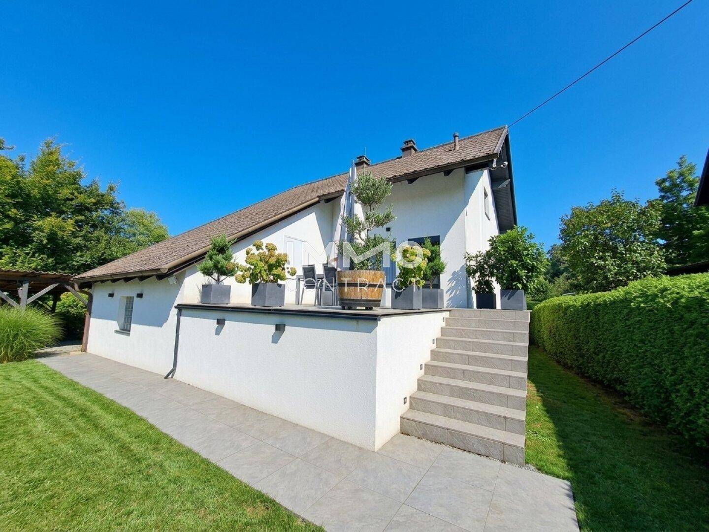 Außenansicht des Hauses mit einer erhöhten Terrasse und Treppe zum Garten.