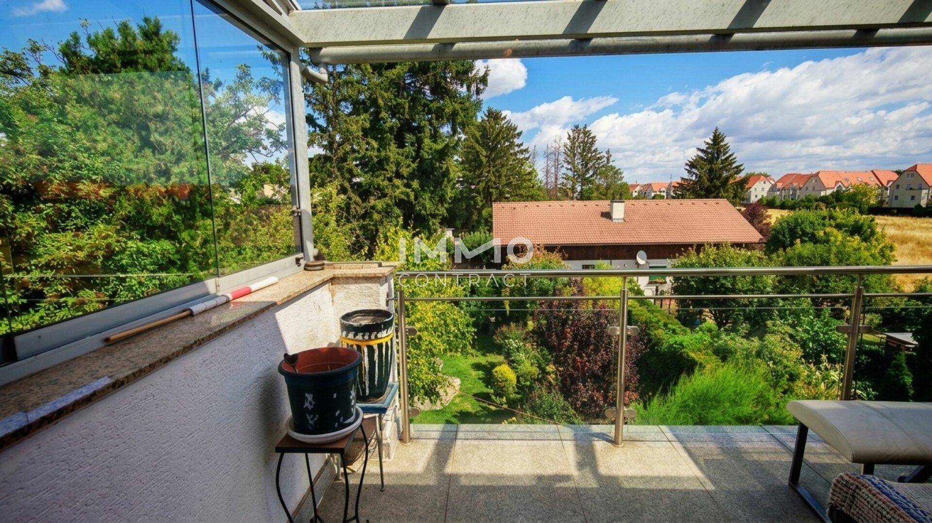 Geräumiger Balkon mit Glasgeländer und weitem Blick auf die grüne Umgebung.