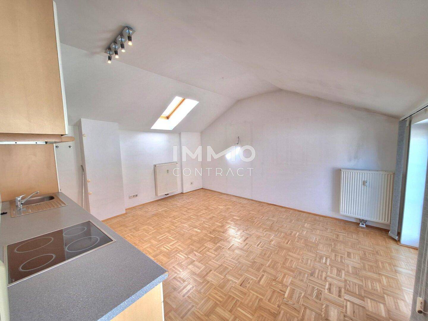Heller Dachgeschossraum mit Parkettboden, Dachfenster und Heizkörper.
