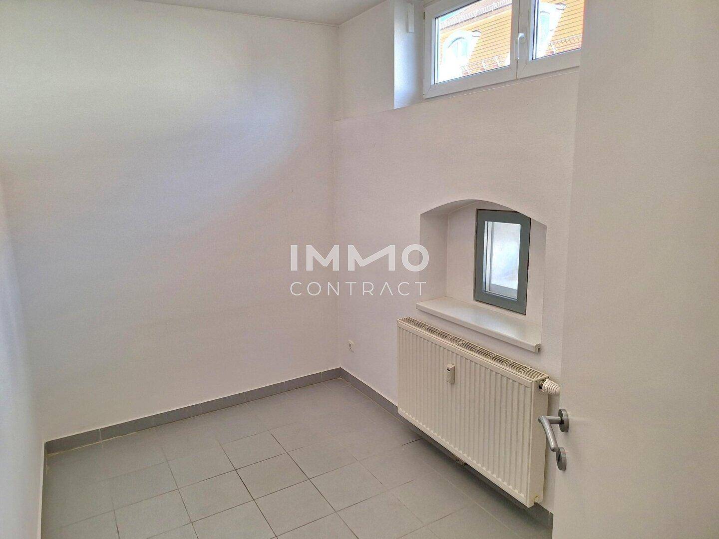 Kleiner Raum mit Fliesenboden, Heizkörper und einem Fenster.