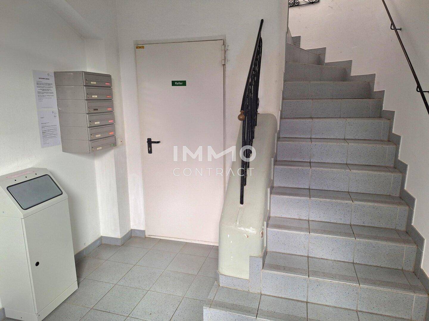 Eingangsbereich mit Treppe, Fliesenboden und Briefkästen im Mehrfamilienhaus.