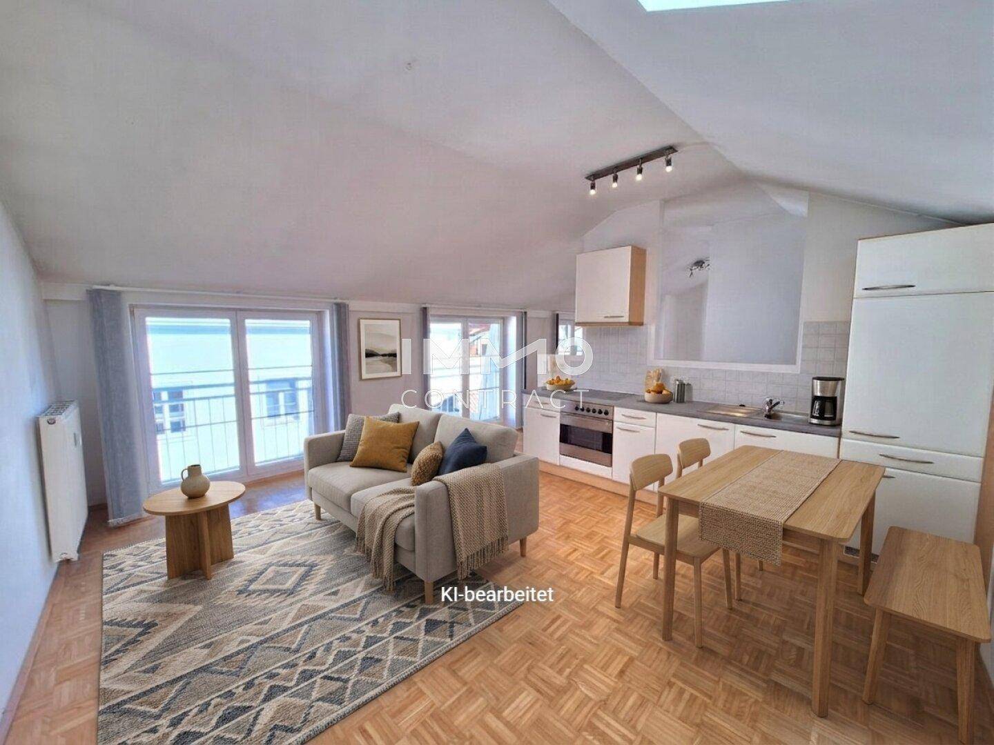 Gemütlicher Wohnbereich mit Sofa, Esstisch und offener Küche unter einer Dachschräge.