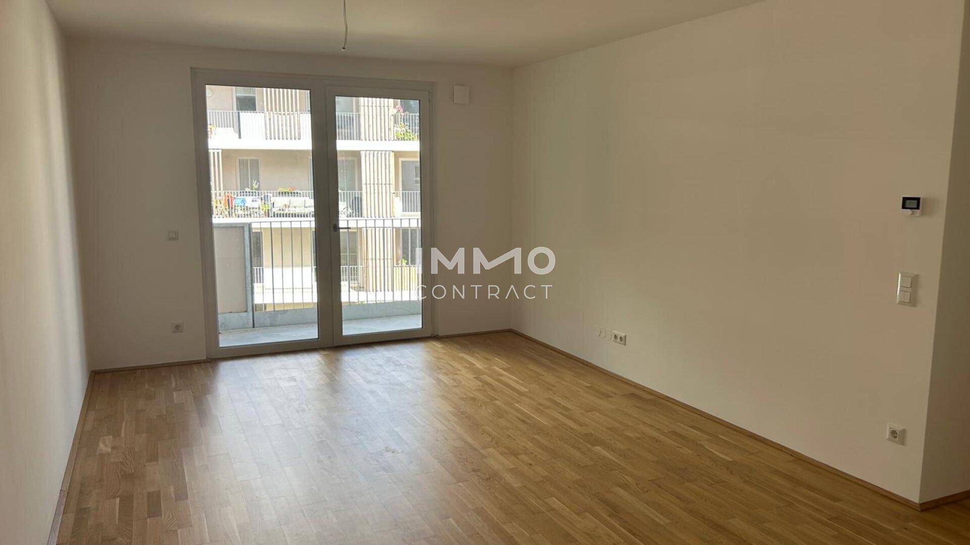 Geräumiges Wohnzimmer mit Holzboden und Zugang zu einem Balkon, bietet viel natürliches Licht.