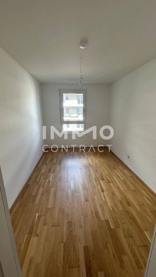 Helles Zimmer mit Holzboden und weiß gestrichenen Wänden, ideal als Schlafzimmer oder Büro.