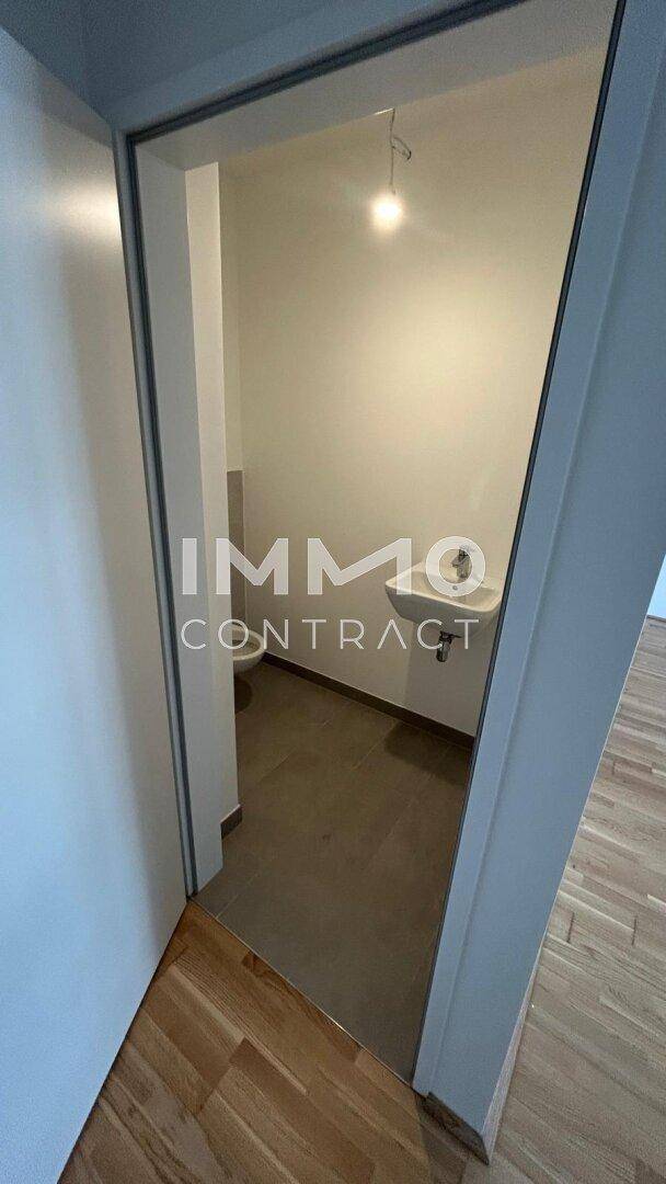 Kleines Gäste-WC mit Waschbecken und Toilette, ausgestattet mit grauen Fliesen.