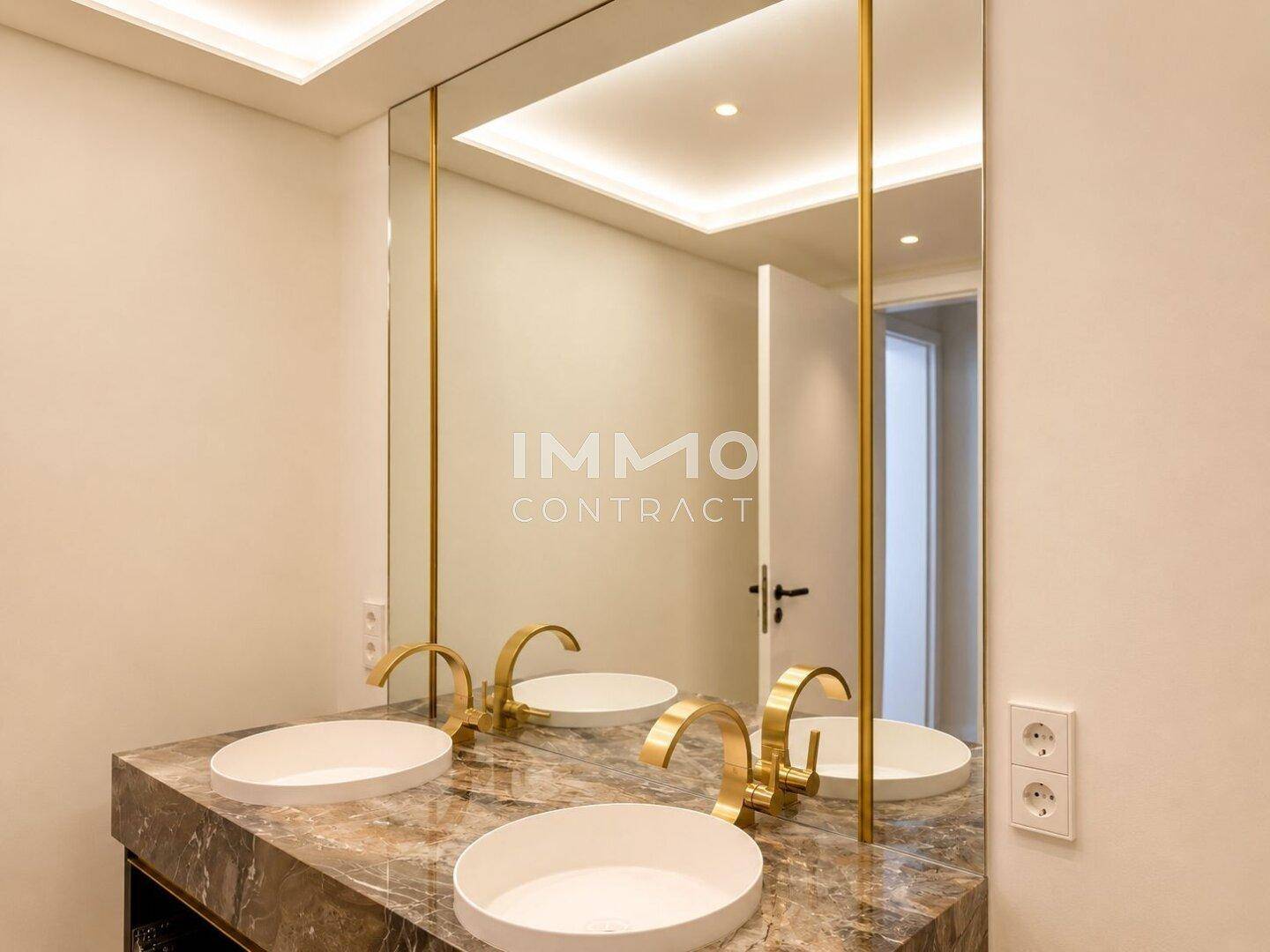 Elegantes Doppelwaschbecken mit goldenen Armaturen und Marmorplatte in einem modernen Badezimmer.