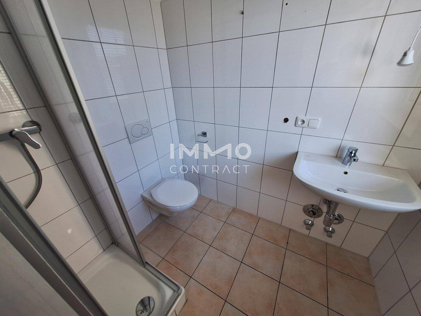 Funktionales Badezimmer mit Dusche, WC, Waschbecken und weißen Fliesen.
