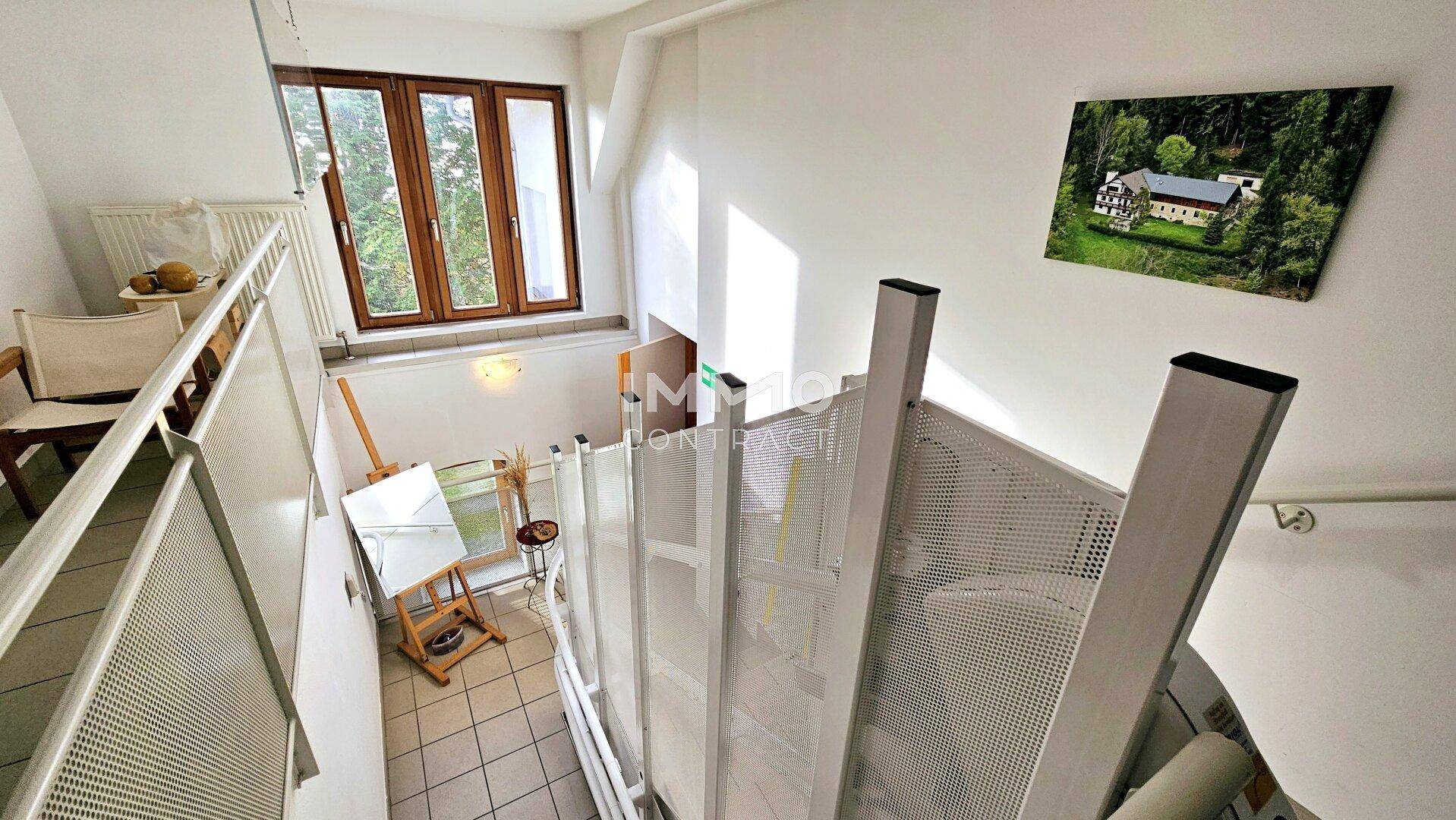 Treppenhaus mit Fliesenboden und einem Fenster, das viel natürliches Licht hereinlässt.