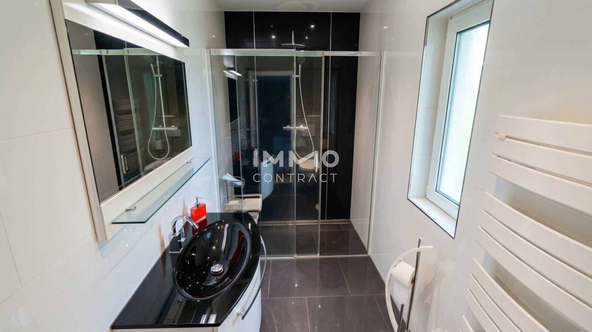 Elegantes Badezimmer mit begehbarer Dusche, schwarzem Waschbecken und modernen Armaturen.