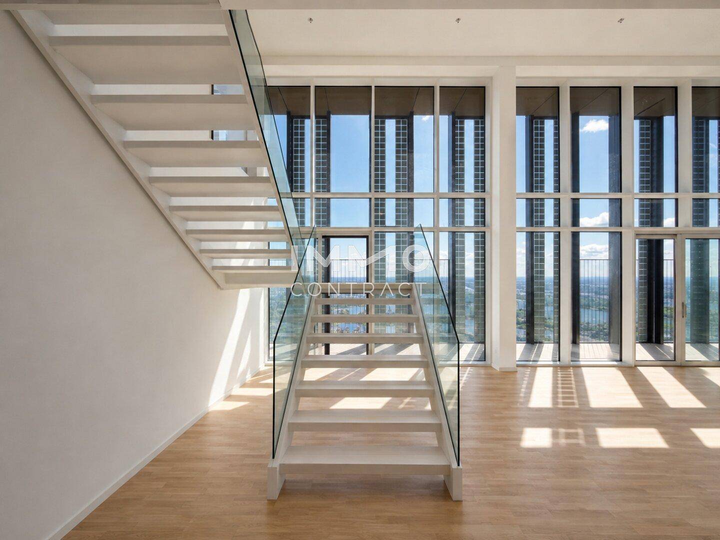 Moderner Wohnbereich mit freitragender Treppe, Glasgeländer und großen Fenstern mit Stadtblick.