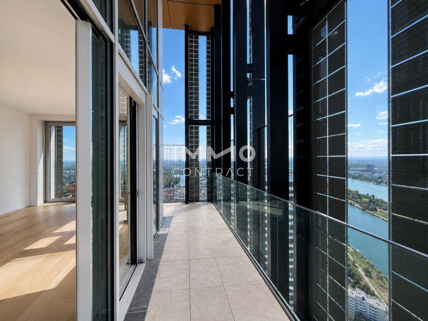 Geräumiger Balkon mit Glasgeländer und atemberaubendem Blick auf die Stadt und den Fluss.