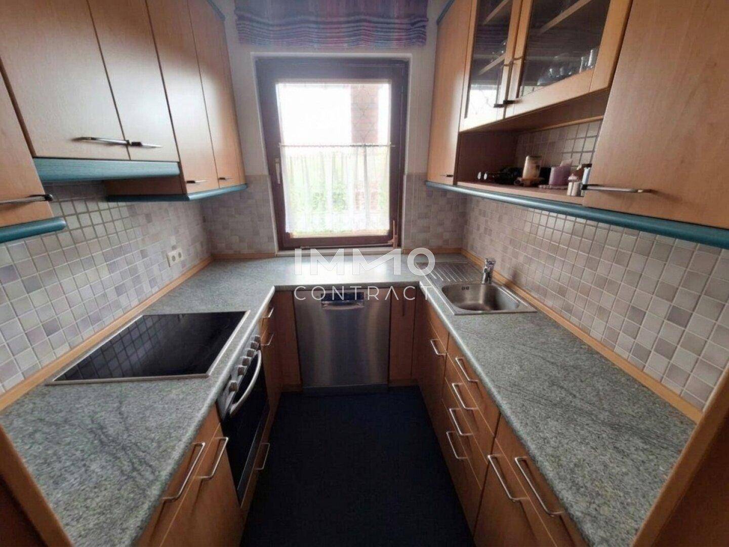 Funktionale Küche mit Holzschränken, Granitarbeitsplatten und Fliesenrückwand.