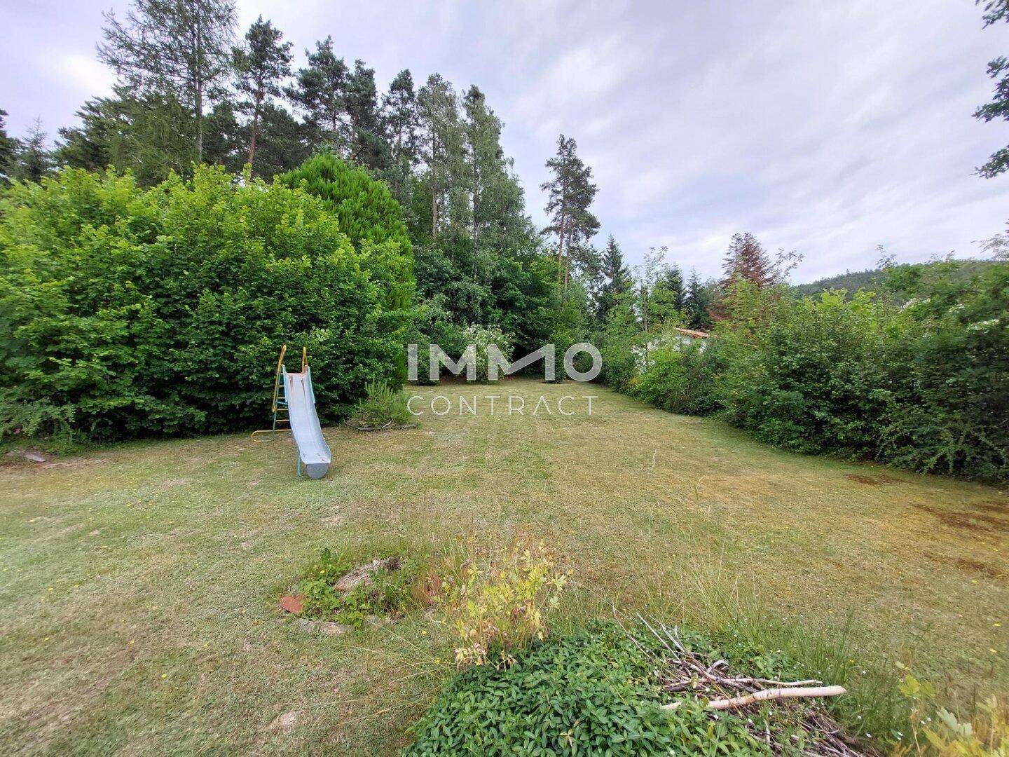Großer Garten mit Rasenfläche und Kinderrutsche, umgeben von Bäumen und Sträuchern.