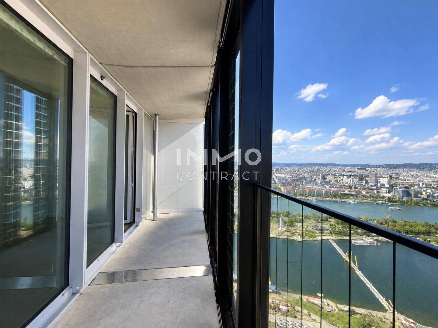 Langer Balkon mit Glasbrüstung und Panoramablick auf die Stadt und den Fluss.