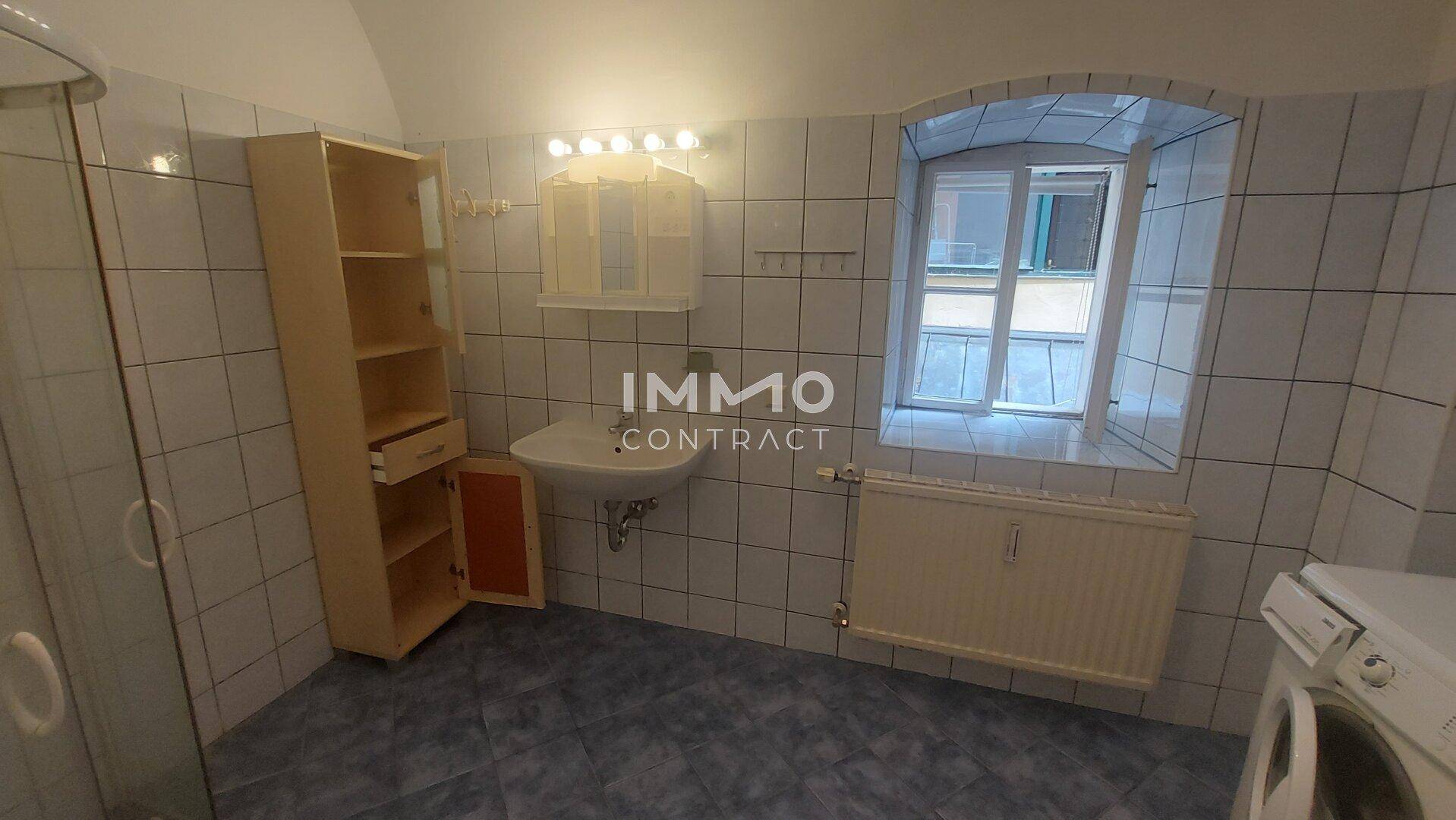 Gefliestes Badezimmer mit Waschbecken, Spiegelschrank und Duschkabine.