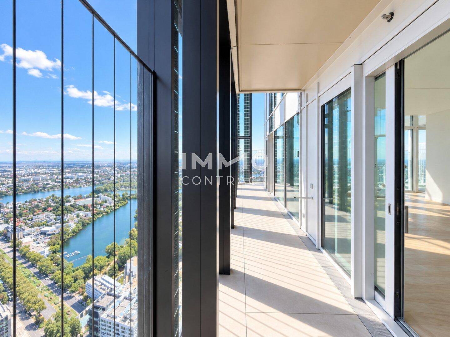 Geräumiger Balkon mit Glasgeländer und weitem Blick über die Stadt und das Wasser.