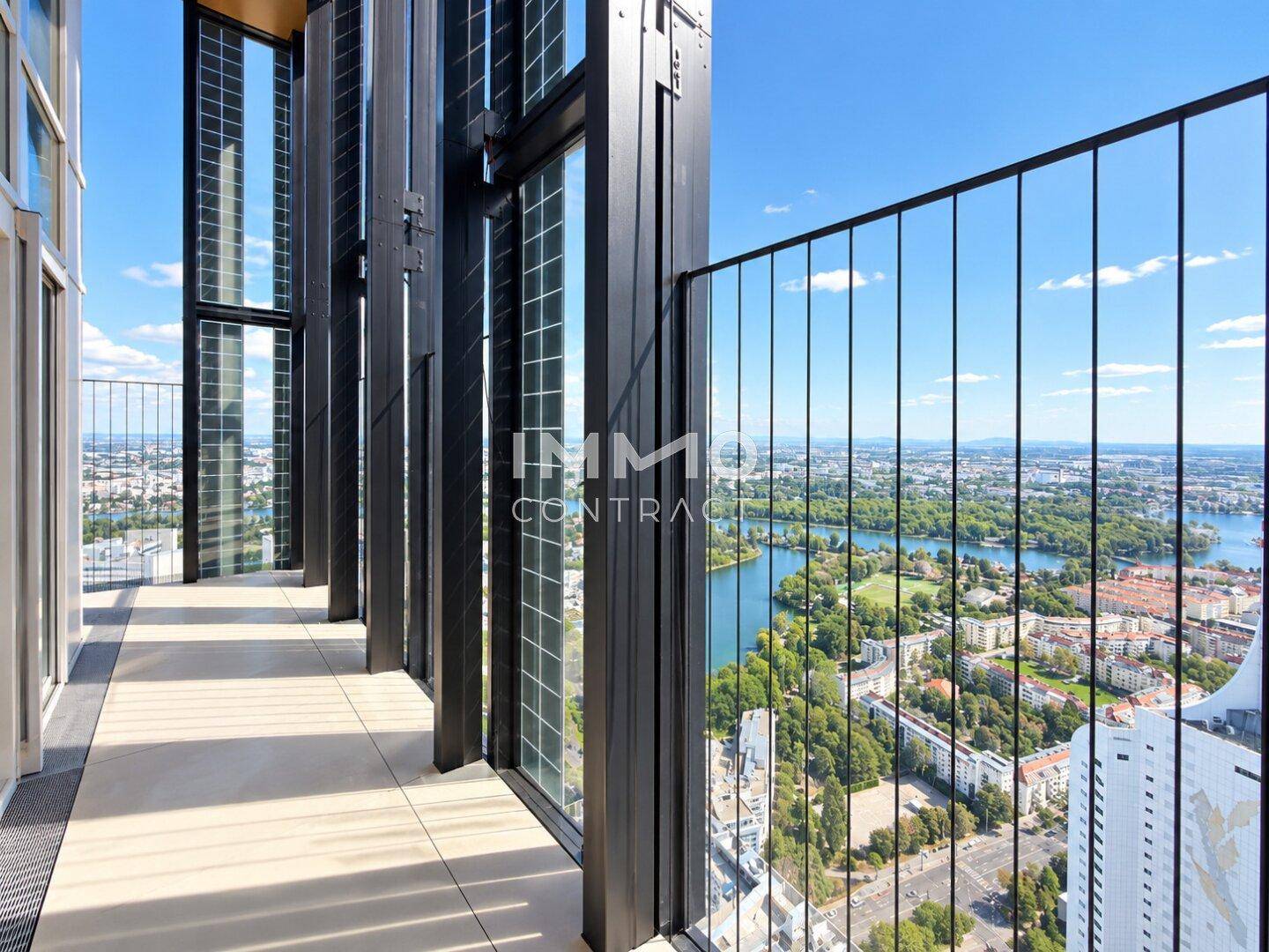 Geräumiger Balkon mit Metallgeländer und atemberaubendem Blick auf die Stadt und den See.
