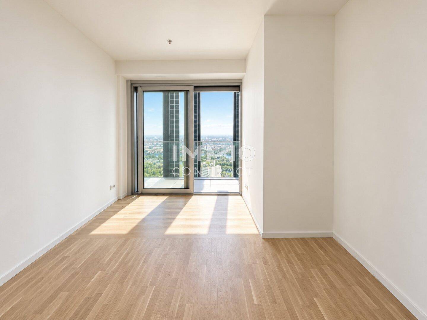 Helles Schlafzimmer mit Holzboden und Zugang zu einem kleinen Balkon mit Stadtblick.