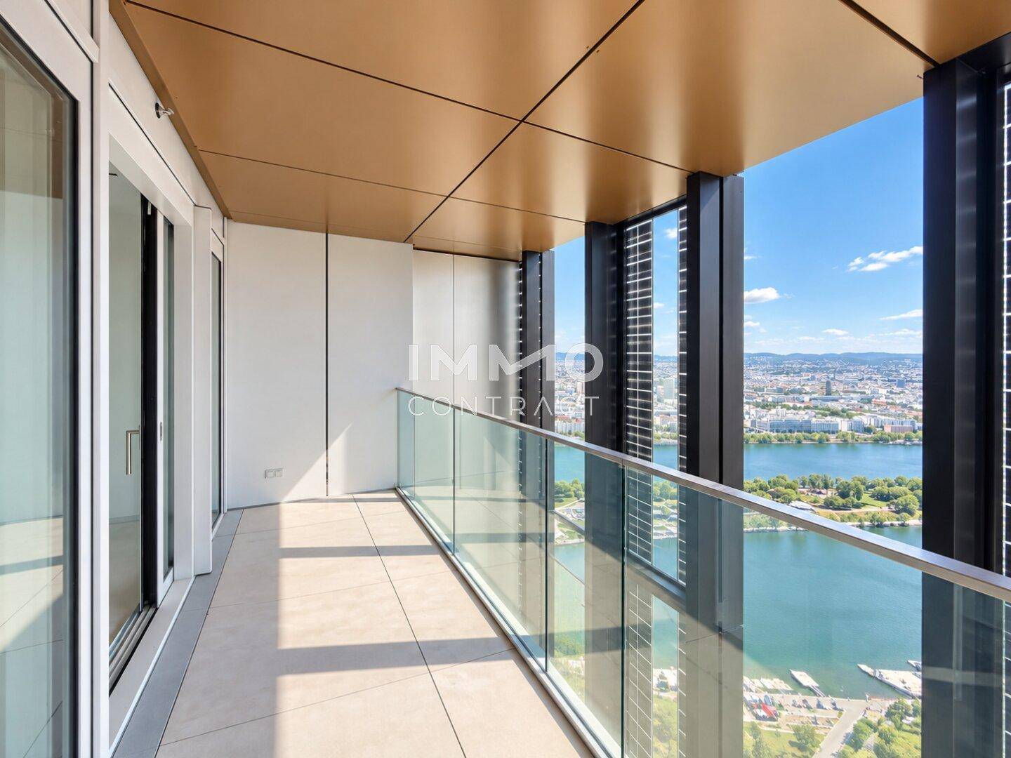 Geräumiger Balkon mit Glasbrüstung, Fliesenboden und atemberaubendem Blick auf die Stadt und den Fluss.