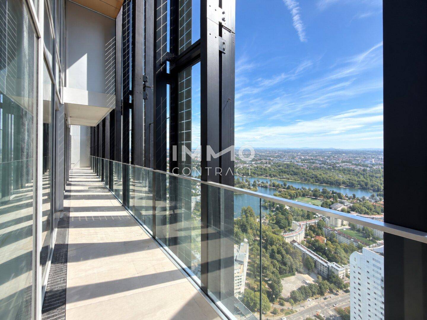 Langer Balkon mit Glasgeländer und atemberaubendem Blick auf die Stadt und den Fluss.