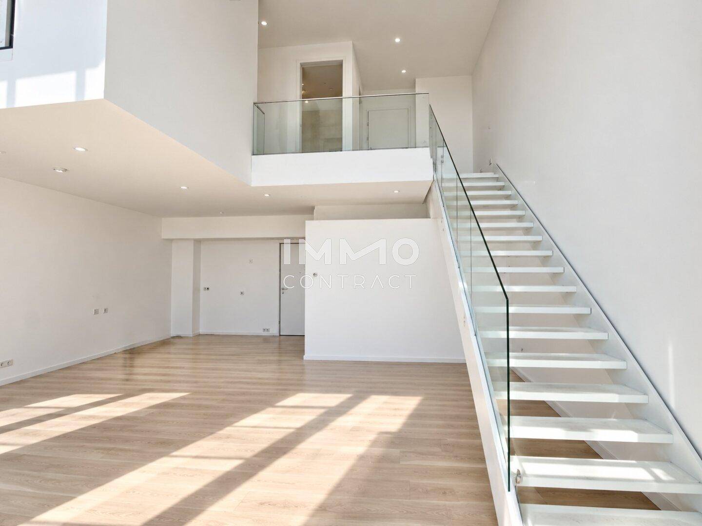 Moderner Wohnbereich mit eleganter Treppe, Glasgeländer und hohen Decken, lichtdurchflutet.