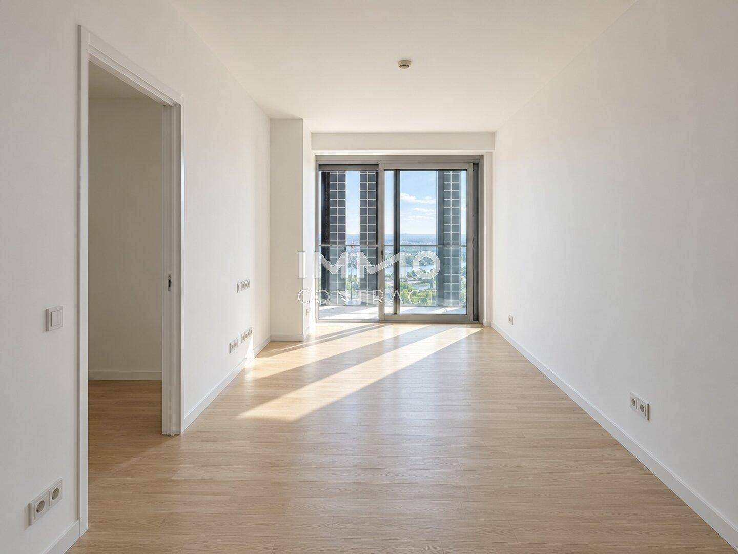 Heller, leerer Raum mit Holzboden und Schiebetür zu einem Außenbereich mit Aussicht.