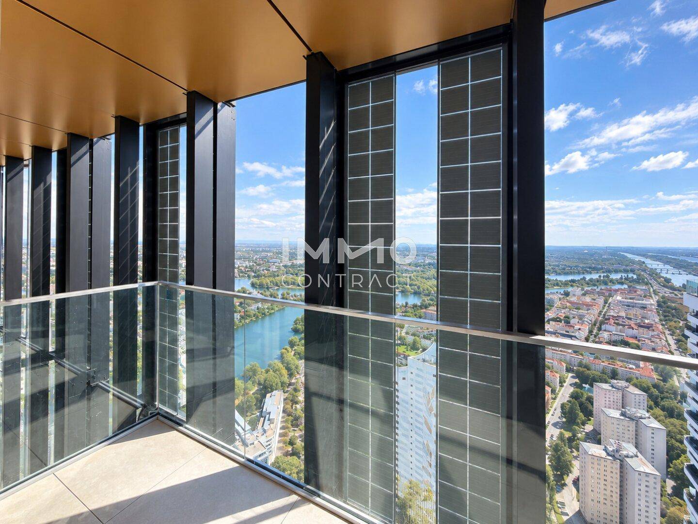 Geräumiger Balkon mit Glasbrüstung und weitem Blick über die Stadt und das Wasser.