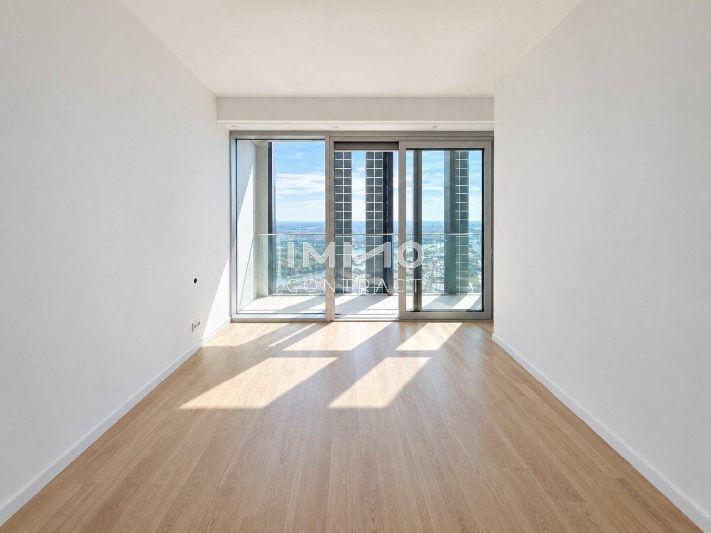 Leeres Zimmer mit großen Fenstern, Holzboden und viel Tageslicht, ideal als Schlafzimmer oder Büro.