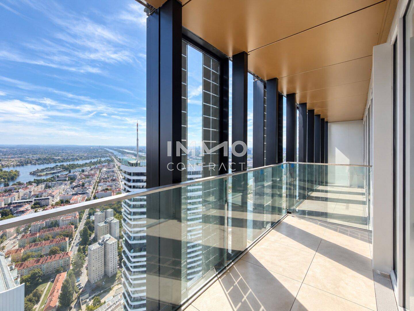 Geräumiger Balkon mit Glasgeländer und atemberaubendem Panoramablick über die Stadt und das Wasser.