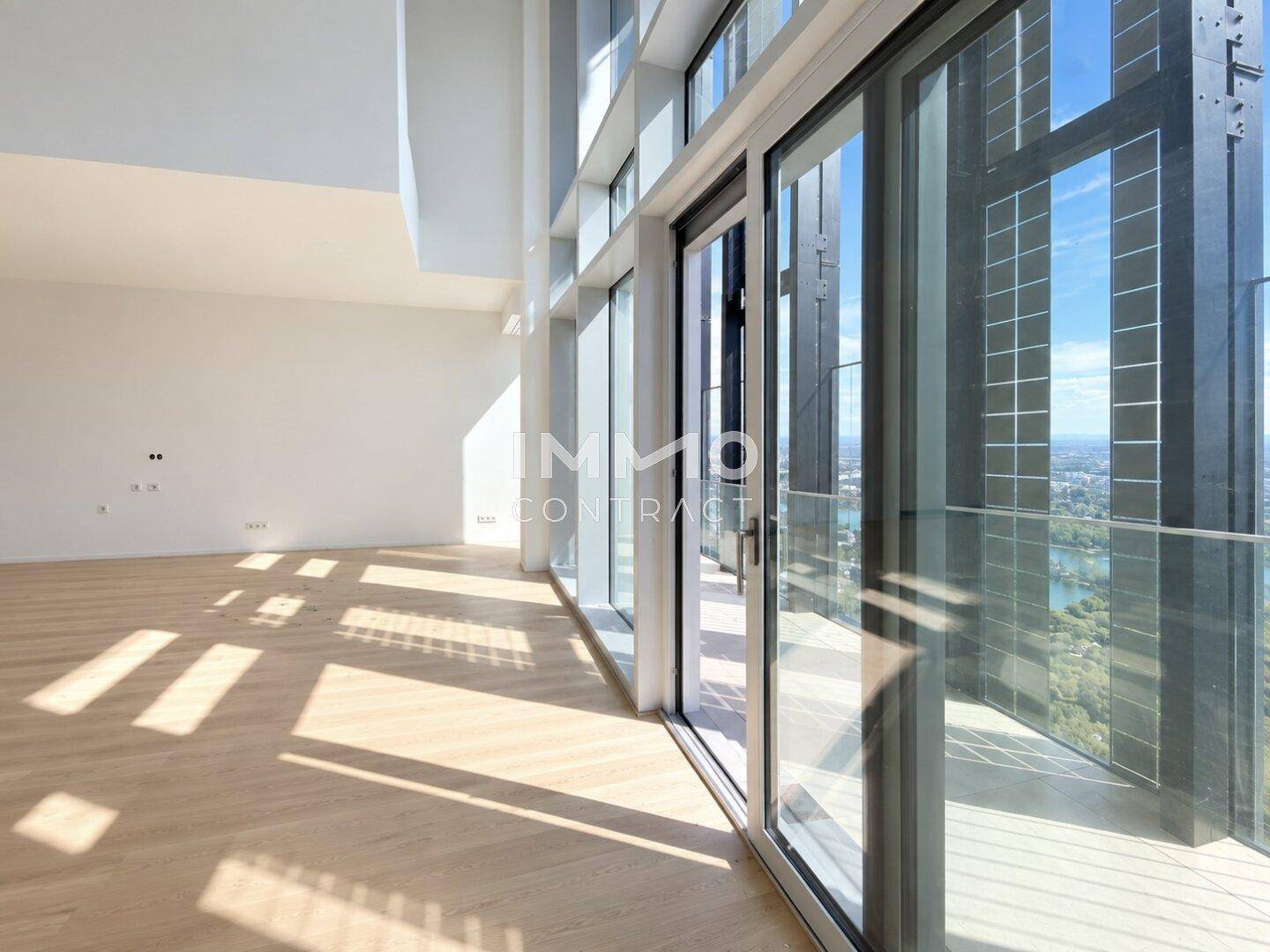 Geräumiger, heller Wohnbereich mit Holzboden und Zugang zu einem Balkon mit Stadtblick.