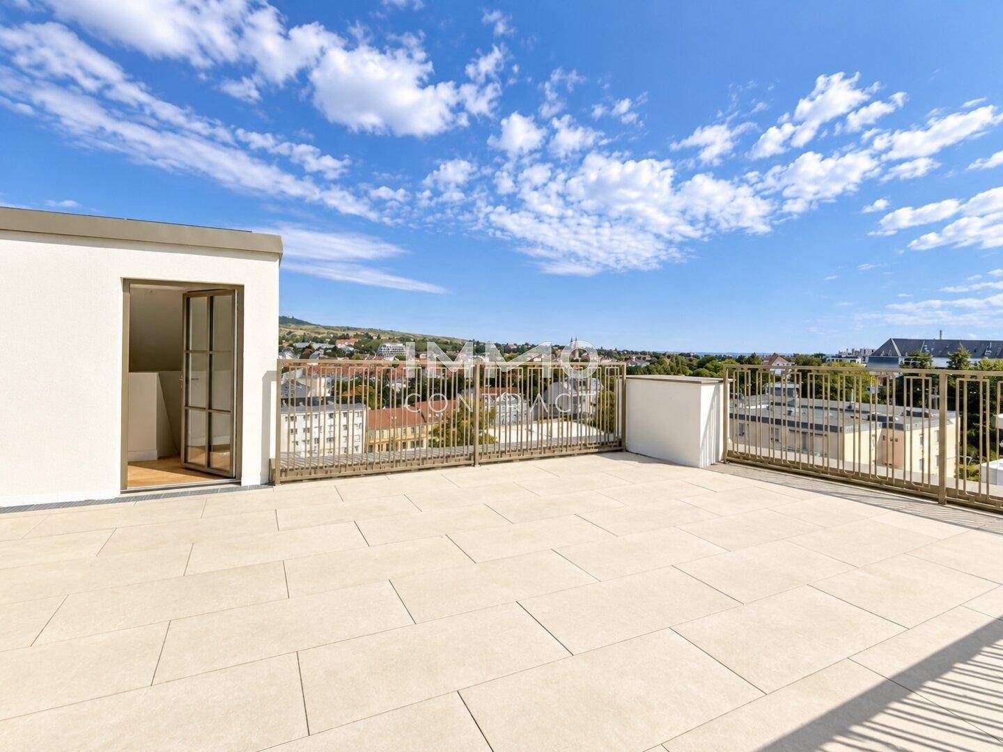 Weitläufige Dachterrasse mit hellem Fliesenboden und Panoramablick über die Stadt.