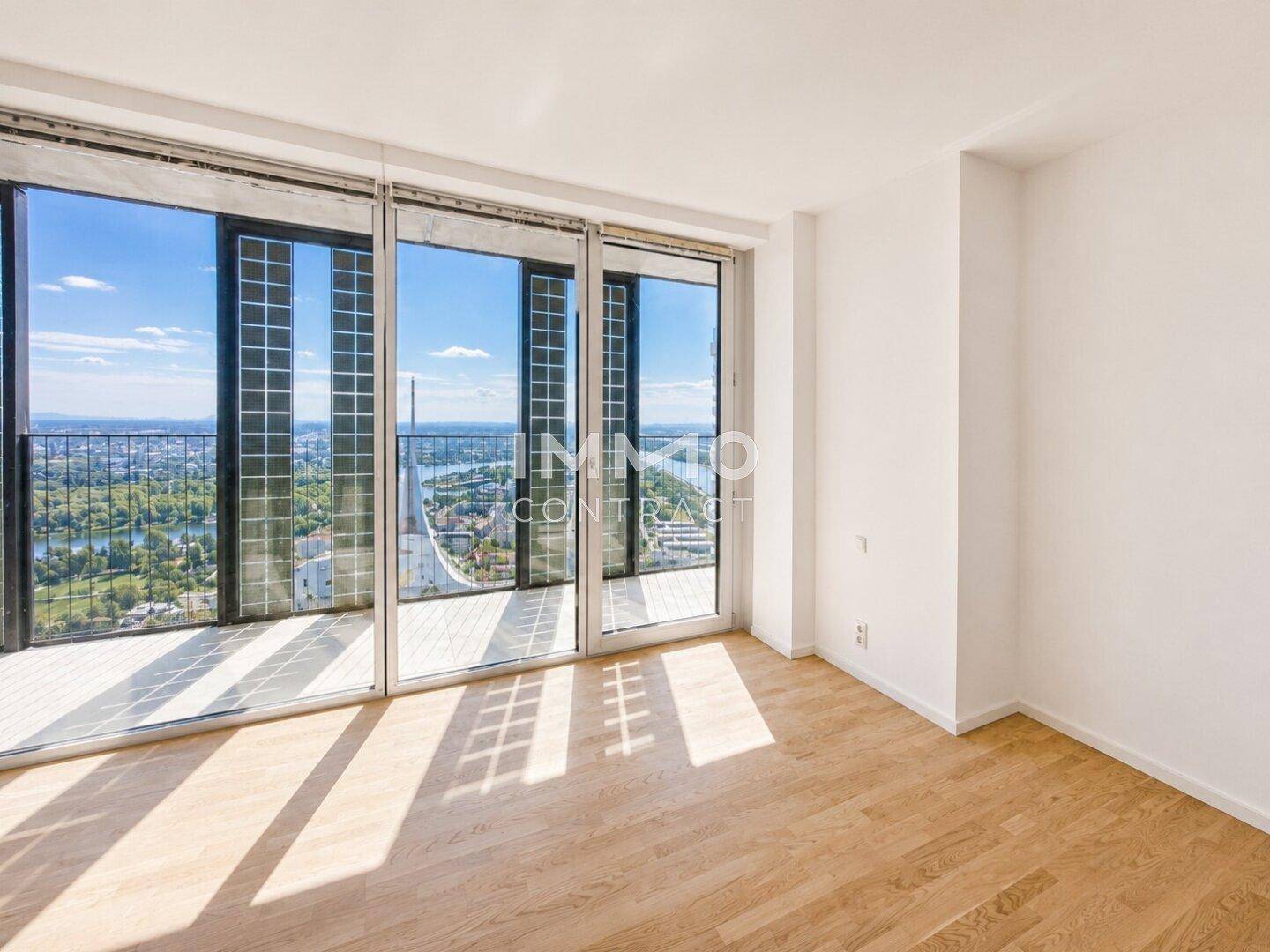Heller Raum mit Parkettboden und raumhohen Fenstern mit weitem Ausblick.