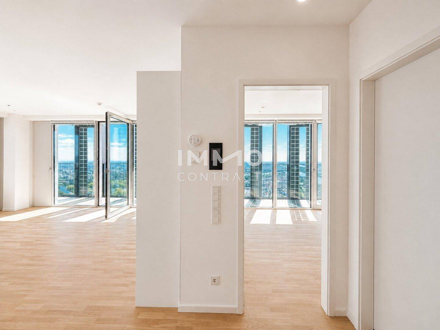 Heller Flur mit Zugang zu verschiedenen Räumen und Blick auf die großen Fenster.