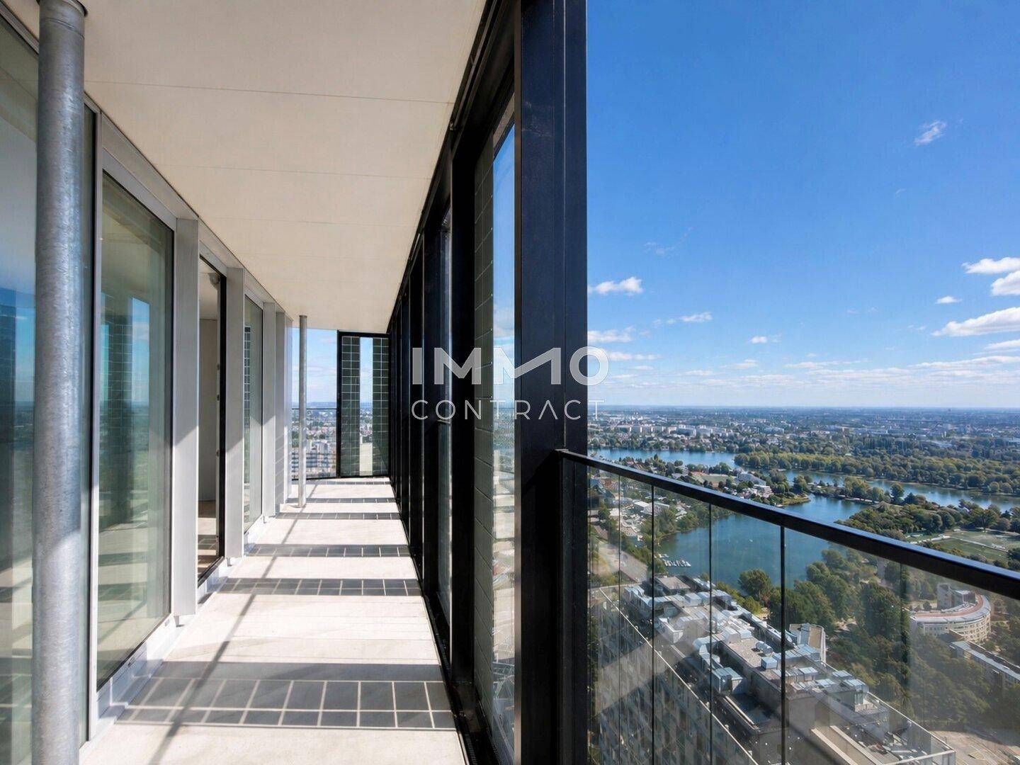 Langer Balkon mit Glasgeländer und weitem Blick über die Stadt und den Fluss.